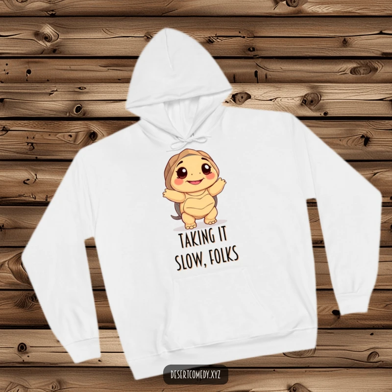 Funny hoodie featuring a smiling desert tortoise with big happy eyes, dancing awkwardly with pure joy and a desert-themed background.